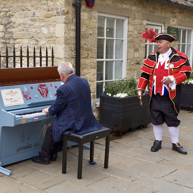 Cirencester Market Place Piano being played by The Reverend Canon Graham Morris (Canon Graham), accompanied by Cirencester Town Crier John Lawrence